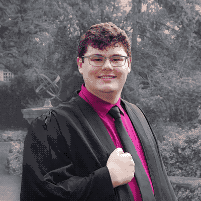photograph of Eric M. Dillon in a pink button-up shirt and black academic dress.